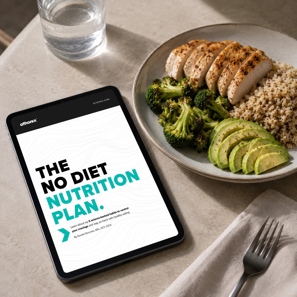 A tablet on a tabletop displaying the Athonix No Diet Nutrition Plan guide next to a healthy meal