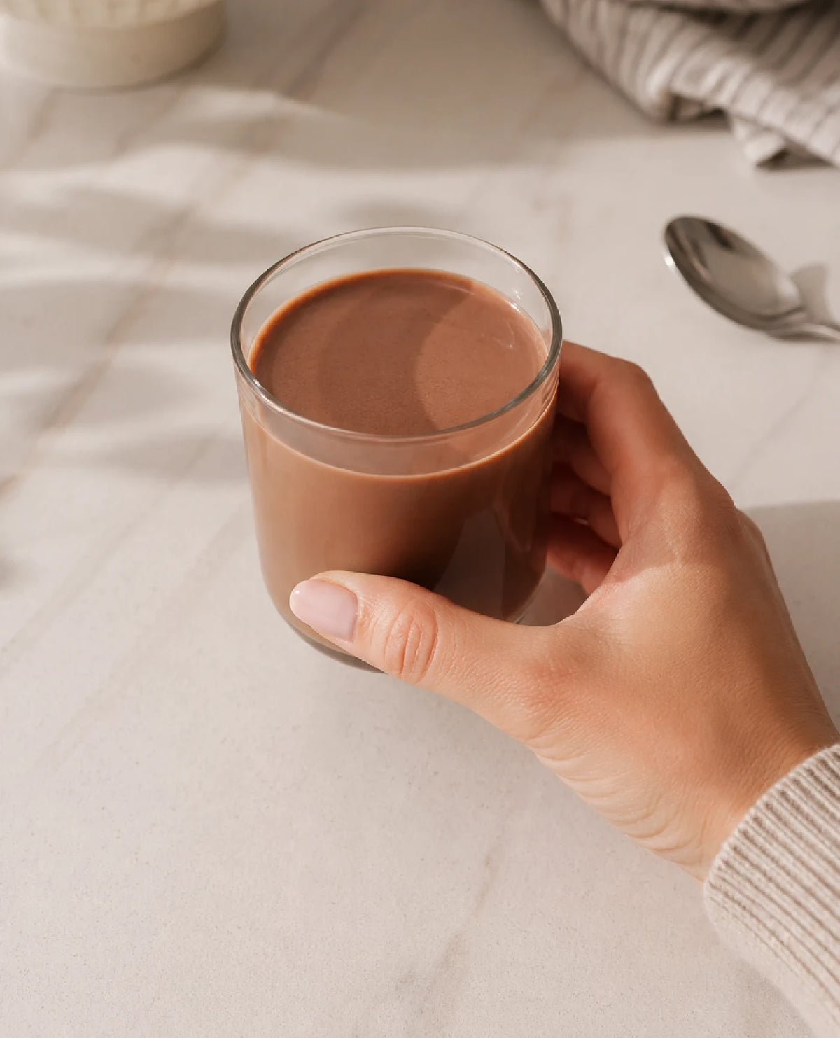 Hand holding a glass of mixed Athonix OFFSET Chocolate Bliss